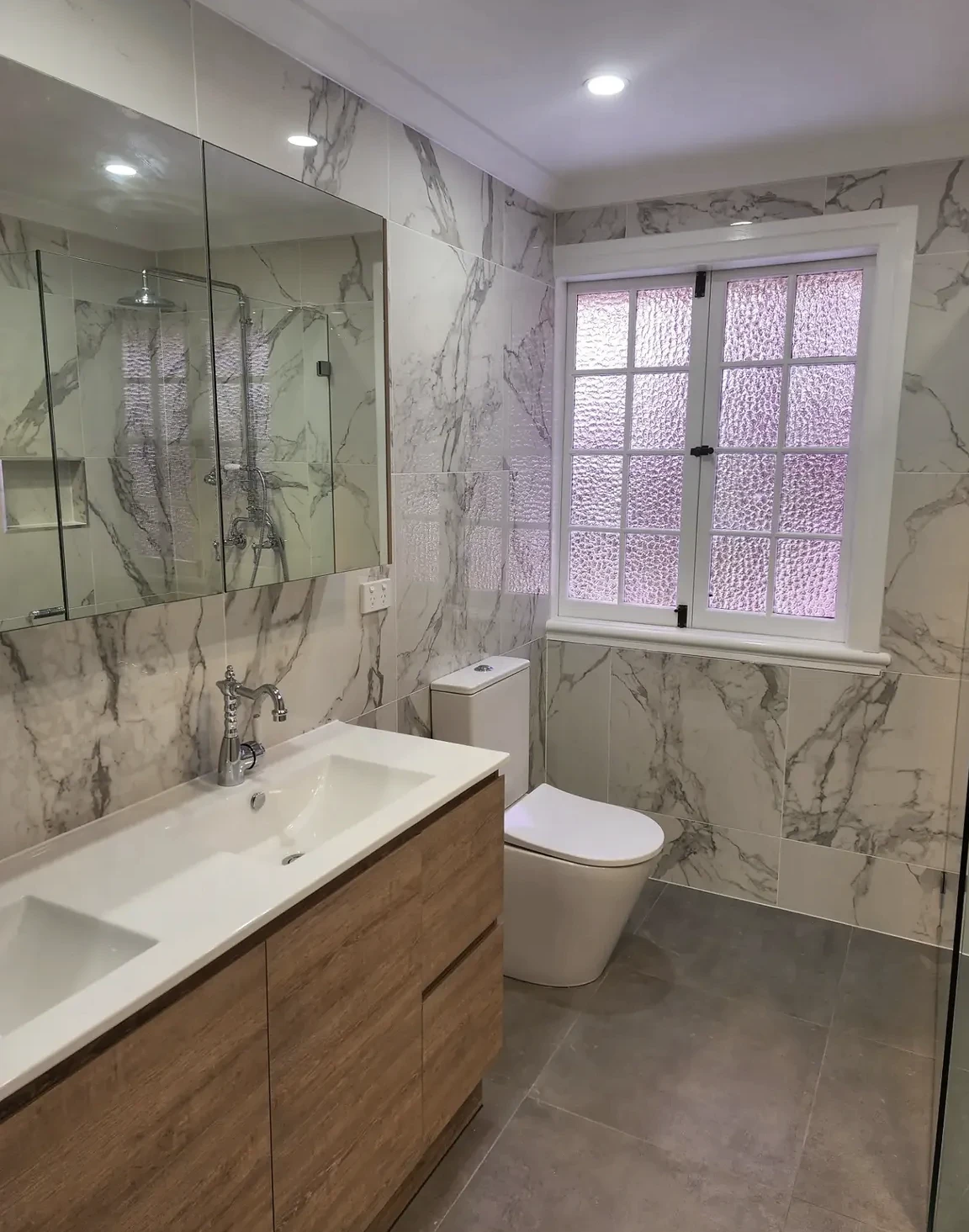 Completed Bardon bathroom, with full-height marble-look wall tiles, a timber vanity and glass shower